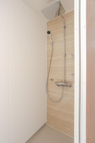 a shower in a bathroom with a wooden wall at A short walk to Akakura Onsen Ski Lift and Town by Japow House in Myoko