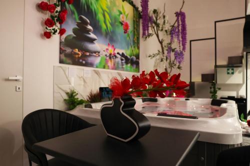 a table with a vase with red flowers on it at Relax in Puglia in Corato