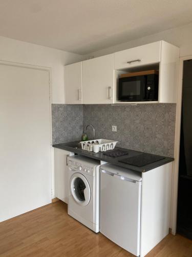 a kitchen with a washing machine and a microwave at T2, accès direct plage, proche thalasso in Cabourg