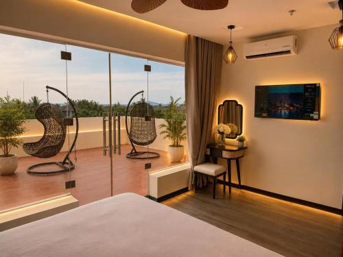 a bedroom with a bed and a balcony with chairs at Asteria Ocean Residence in Danang
