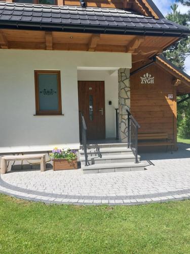 a house with a porch and stairs in front of it at ZYCH - Domek in Chochołów