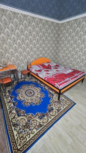 a bedroom with a bed and a table and a rug at Гостиница Саян in Shymkent