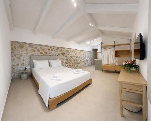 ein Schlafzimmer mit einem großen weißen Bett und einem Schreibtisch in der Unterkunft Villa Anthousa luxury villas and suites in Anthoúsa