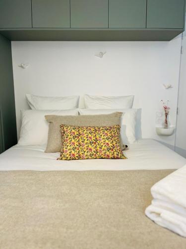 a large white bed with a colorful pillow on it at La Maison Kerguelen - Suite in Quimper