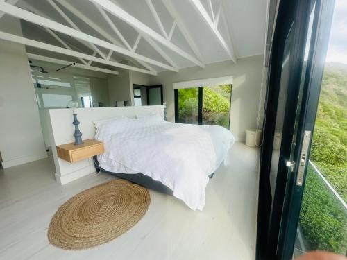 a bedroom with a white bed and a large window at Sunset Villa Herolds Bay in Herolds Bay