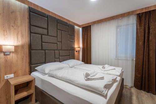 a bedroom with a white bed with a wooden headboard at Maiskogelblick Apartments by we rent in Piesendorf