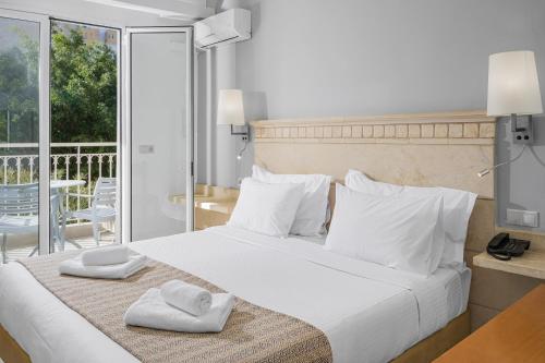 ein Schlafzimmer mit einem großen weißen Bett, auf dem Handtücher liegen in der Unterkunft Glaros Beach Hotel in Hersonissos