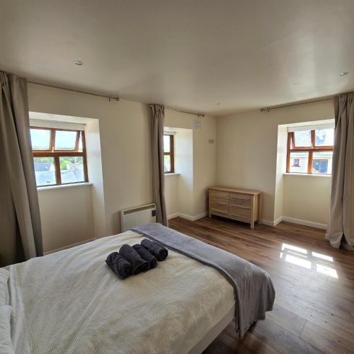 a bedroom with a large bed with two windows at 18 Clifden Court in Clifden