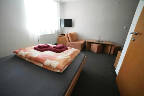 a bedroom with a bed and a chair and a table at Penzion Ajda in Liptovský Mikuláš