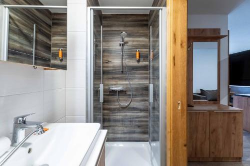 a bathroom with a shower with a sink and a tub at Maiskogelblick Apartments by we rent in Piesendorf