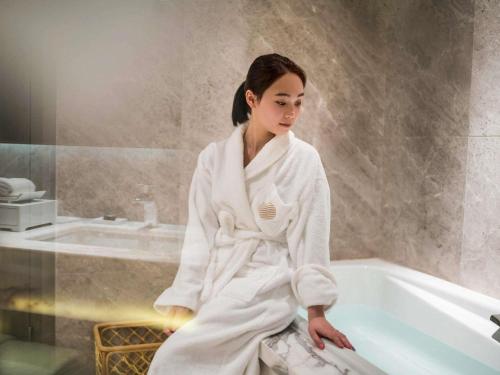 a woman sitting on the edge of a bath tub at Pullman Zhuhai in Zhuhai