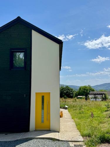 a small building with a yellow door next to a field at Nettles & Petals in Kenmare
