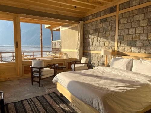 a bedroom with a bed and a desk with a view of the ocean at Dera Lamsa Resort Shigar in Shigar