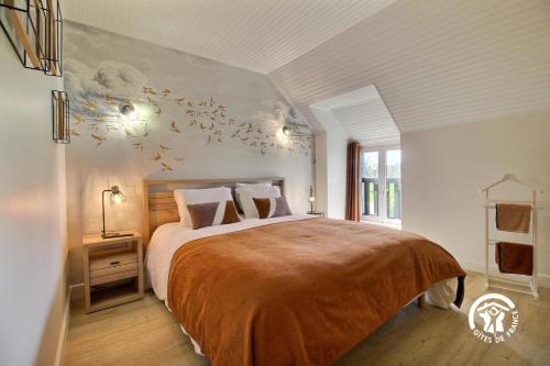 a bedroom with a large bed with birds on the wall at Des puits in Locoal-Mendon