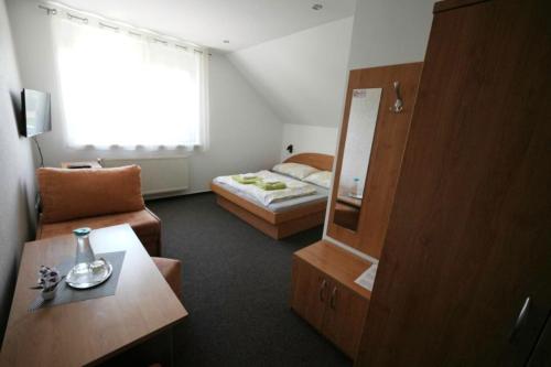 a small room with a bed and a mirror at Penzion Ajda in Liptovský Mikuláš
