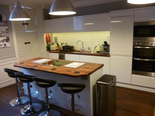 a kitchen with a counter with stools and a sink at Kings House Wokingham in Wokingham