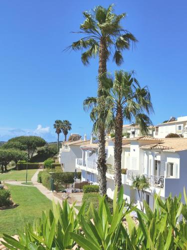 a white building with palm trees in front of it at Villa Sunrise by MOJE Holiday in Budens