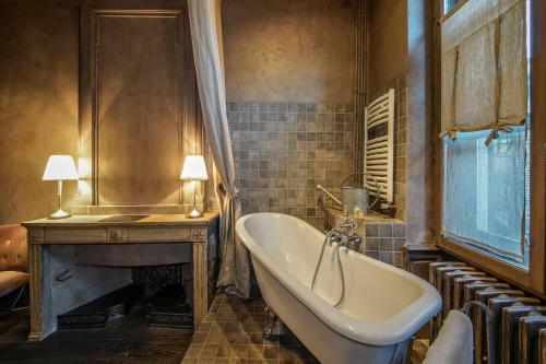 a bathroom with a bath tub and a fireplace at Hôtel de la Tour in Châtillon-sur-Chalaronne
