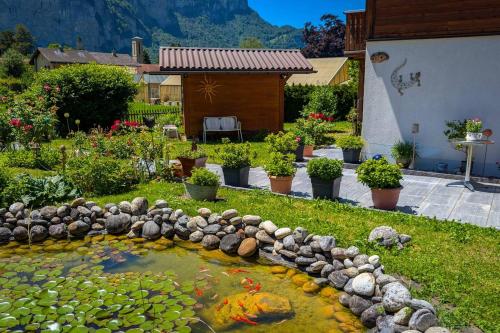 a koi pond in a garden with a house at Gemütliches Gartenhüttli mit Alpenblick in Meiringen