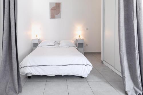a bedroom with a white bed with two night stands at Nüma Studio - Orly Paris in Montgeron