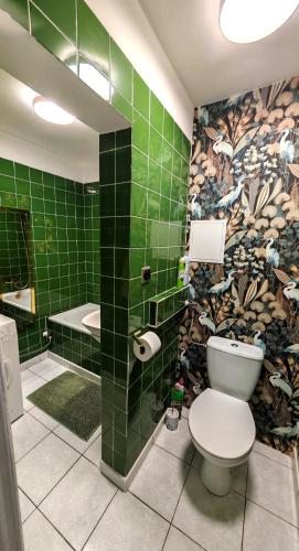 a bathroom with a toilet and a green tiled wall at Sen nad Bałtykiem - Apartament z balkonem, Ustka in Ustka