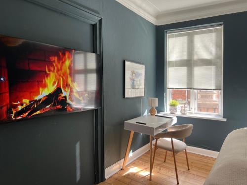 a room with a fireplace with a table and a chair at Greenbrook Blue Suite in Aalborg