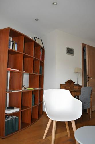 a white chair in front of a book shelf at Chambre d'hôte l'Argentier in Noyarey