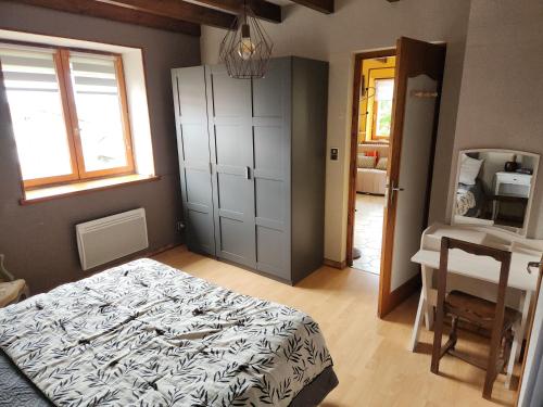 a bedroom with a bed and a desk and a window at Les Souchottes, charmante maisonnette in Bulligny