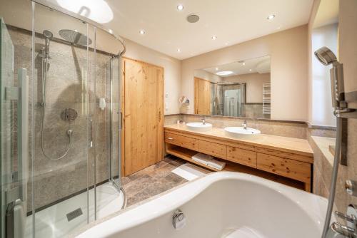 a bathroom with two sinks and a tub and a shower at Natur & Alpinhotel Post in Vent