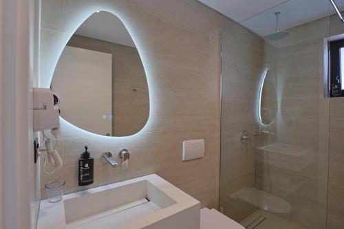 a bathroom with a shower and a sink and a mirror at Hotel Danedi in Ksamil