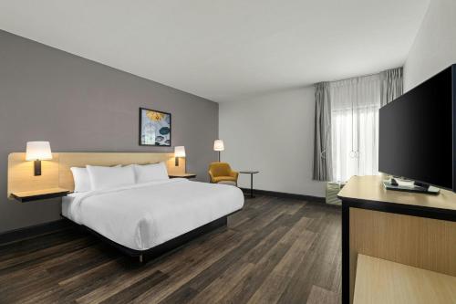 a hotel room with a bed and a flat screen tv at City Express by Marriott Yulee in Yulee