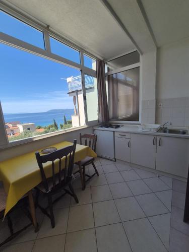 a kitchen with a table and chairs and a large window at Guest House Čović in Tučepi