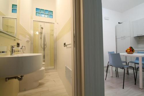 a bathroom with a sink and a table with chairs at Residence Savoia in San Vito lo Capo