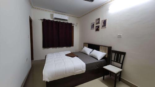 a small bedroom with a bed and a chair at BMK Inn in Bangalore