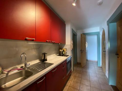 a kitchen with red cabinets and a sink at Seehaus Simssee in Stephanskirchen