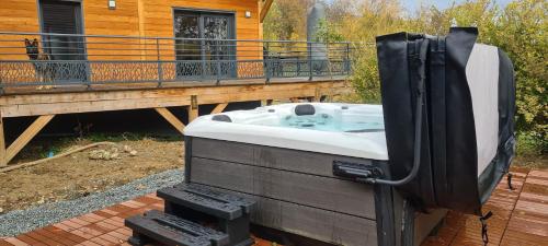 a bath tub sitting on a deck next to a house at Chalet avec jacuzzi privé, 3 chambres in Traubach-le-Haut