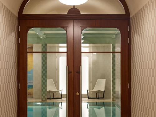 a glass door with two chairs in a room at Cures Marines Hotel Thalasso & Spa Trouville - MGallery Collection in Trouville-sur-Mer