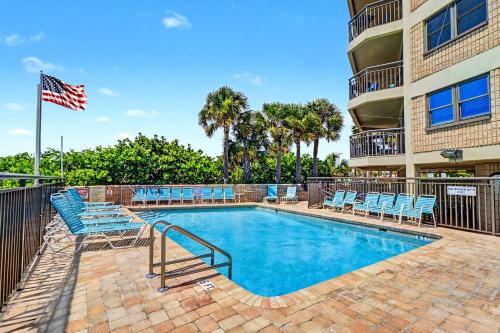 a swimming pool with chairs and an american flag at Gulf Strand Resort 308 in St. Pete Beach