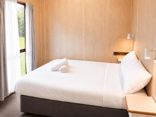 a bedroom with a large white bed with a window at Shady Acres Caravan Park in Warrenheip