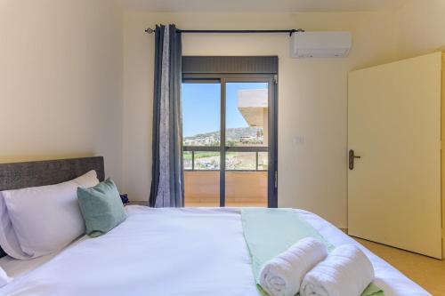 a bedroom with a large white bed with a window at Mauve et Miel 2-BR Apartment In Batroun in Batroûn