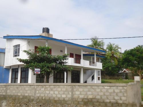a white house with a blue roof behind a wall at Masha Beach Inn in Tangalle