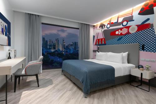 a bedroom with a bed and a desk and a window at Oakwood Studios Sukhumvit Bangkok in Bangkok