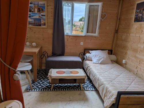 a small room with a bed and a desk and a window at Studio bois avec jardinet in Parentis-en-Born