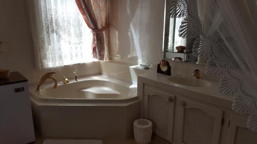 baño con bañera, lavabo y ventana en Bokmakierie Country Lodge, en Ladysmith