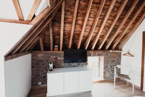 a room with a brick wall and a flat screen tv at La MASSERIA in Thuin