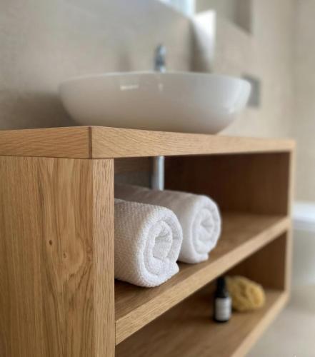 a shelf with towels and a sink in a bathroom at Fischerhof in Cortaccia