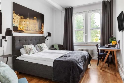 a bedroom with a bed and a desk and windows at Frimurarehotellet; Sure Hotel Collection by Best Western in Kalmar