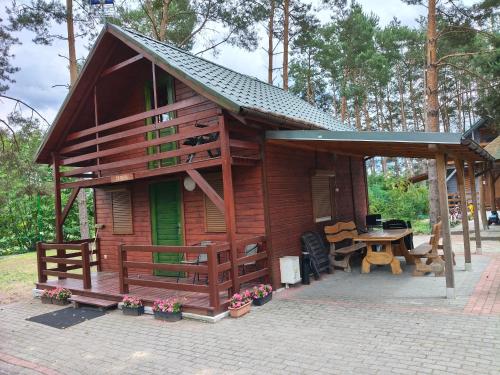a small wooden cabin with a table and a patio at Domki Piaskowa in Boszkowo-Letnisko