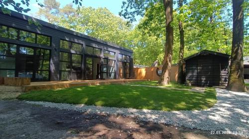 an exterior view of a house with a grass yard at Luxe chalet midden in de natuur in Rijen
