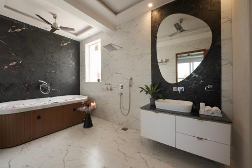 a bathroom with a tub and a sink and a mirror at Saffronstays Olive Farms in Mandkaula